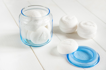 white zephyr on white wooden background. marshmallow in decorative glass jar