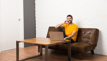Man with his laptop in a room talking to mobile