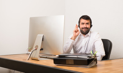 Telemarketer man in a office with fingers crossing and wishing the best