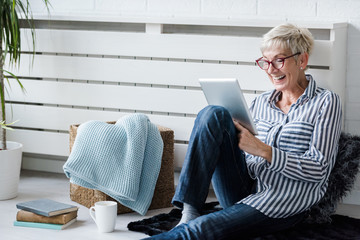 Smiling beautiful senior woman using digital tablet at home