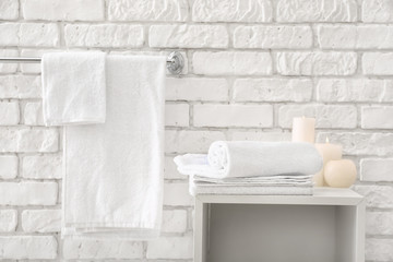 Towels with candles near white brick wall