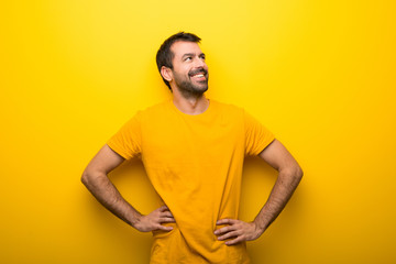 Man on isolated vibrant yellow color posing with arms at hip and laughing