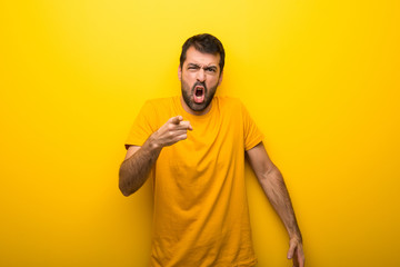 Man on isolated vibrant yellow color frustrated by a bad situation and pointing to the front