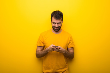 Obraz premium Man on isolated vibrant yellow color sending a message or email with the mobile