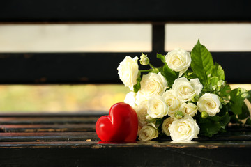 Bouquet of beautiful roses with red heart on wooden bench outdoors
