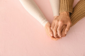 Loving young couple holding hands on color background