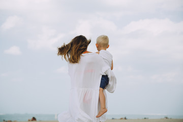 Young mother carrying her little son at the beach