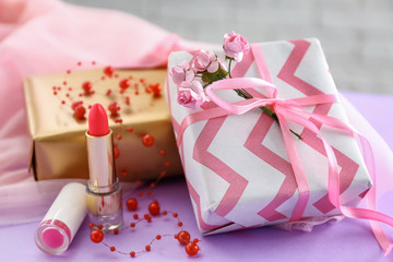 Beautiful gift boxes with lipsticks on color table