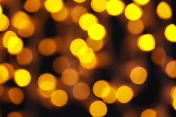Glowing Christmas lights on dark background, blurred view