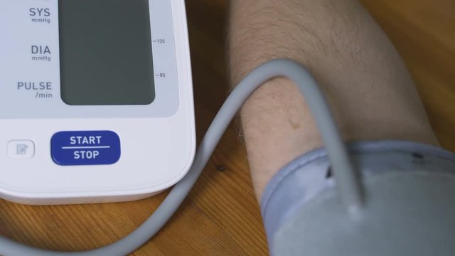 A man measures his blood pressure with a tonometer at home. Close-up view of the tonometer display and the hand of a man