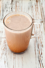 A glass cup of cocoa on a white wooden background. Close up