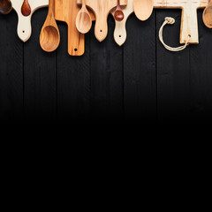 Top view of assorted wooden spoons and chopping boards on black wooden table with black gradient. Food background concept. Copy space.