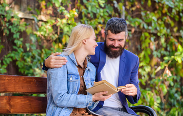 Fototapeta premium Read same book together. Couple interested literature. Literature common interest. How to find girlfriend with common interest. Meeting people with similar interests. Man and woman sit bench park