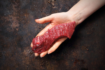 Wołowina. Kawałek surowego mięsa wołowego na kobiecej dłoni. - obrazy, fototapety, plakaty