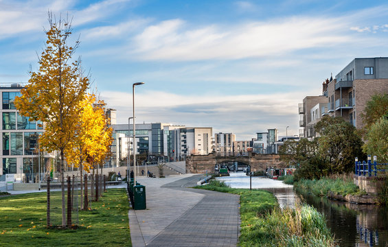 Cityscape of Edinburgh, Scotland, showing Union Canal walkway with autumnal yellow trees on the side, Viewforth bridge in the background and modern buildings around. Urban landscape. Architecture