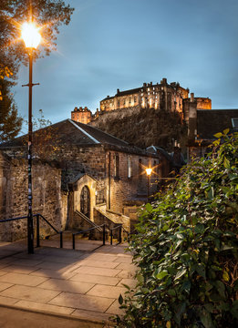 View of Edinburgh's Castle, in Scotland, from The Vennel steps at dusk, with street lights and lights in the castle on. Travel. Cityscape. Urban landscape