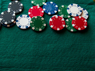 Poker chips of various colors on a green mat