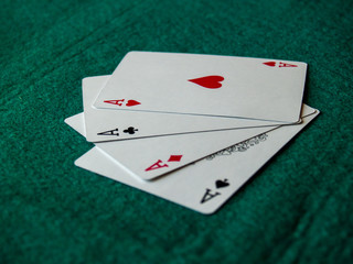 The four aces of a poker deck on a green mat