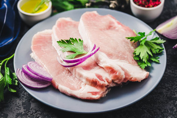 Raw fresh meat slices on plate, dark background. Selective focus, space for text.