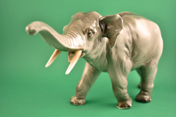 Fototapeta na wymiar Realistic elephant statue stock images. Old porcelain statue of an elephant. Figurine elephant stock images. Elephant isolated on a green background
