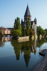Beautiful grey french castle in Metz in the summer day with green trees around it near the river