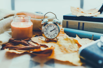 vintage clock on the background of autumn leaves Autumn shot with a candle and a clock