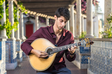 Fado musician playing on portuguese guitar under pergola in Lisbon, Portugal