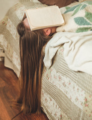 Beautiful young woman sleeping on bed with book covering her face because reading book with preparing exam of college