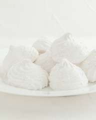 Fototapeta na wymiar Delicate, white, fruit marshmallows. On a white background in a white plate. Isolated. Blurred background.