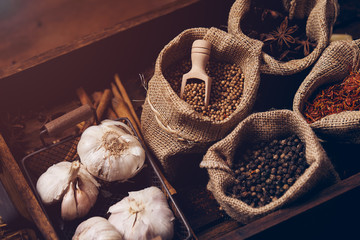 Close up of spices such as star anise, anise seeds, black pepper in burlap placing together with garlic in wooden tray
