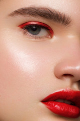 Naklejka premium Closeup of beauty woman with clean shiny skin and bright makeup. Fashion, spa, cosmetology, injections into red lips, shadows on brown eyes and thick eyebrows, cosmetics, makeup, beautiful
