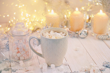 Obraz na płótnie Canvas Coffee cup with marshmallows, candles on wooden table. Christmas holiday background. cozy still life. festive winter season. template for design