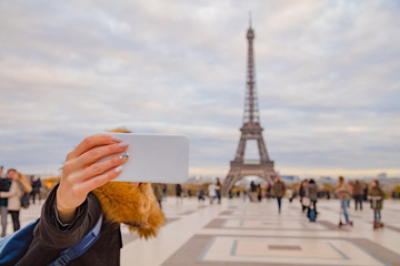 Girl using cellphone with Paris city background and Eiffel tower.