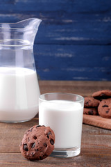 Tasty sweet cookies with chocolate and milk on a brown wooden table and on a blue background