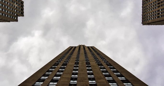Timelaps of cloudy sunny day with building on the background. Brick residential building with dramatic clouds moving fast. Corporate Building, graay Sky and Clouds.
