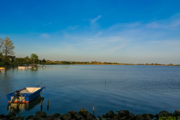 Beautiful quiet scenery of a waterside with tied up motorboats and a village in the background on Fehmarn island in Germany at dusk.   