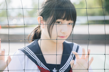 Portrait of beautiful Asian japanese high school girl uniform looking with net in green background