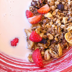 Square closeup of delicious traditional granola with yogurt, strawberry, raisins, nuts and fruits