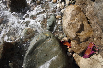stones in the water and old sandals