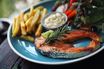 Roasted salmon steak , baked salmon with salad fresh vegetable pm wooden table