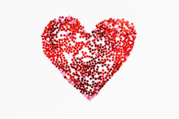 Heart made of sparkling red conffetti. Shining symbol of love on white background.