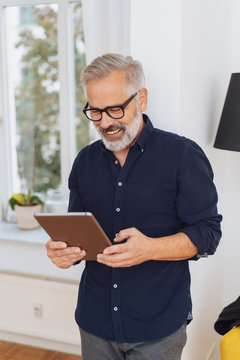 Man smiling happily as he reads a tablet-pc