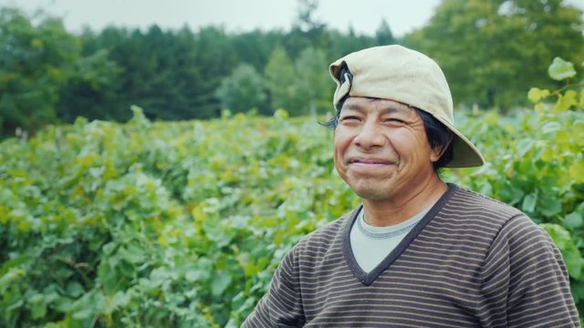 Portrait of a smiling mexican farmer. Standing on the field, looking at the camera