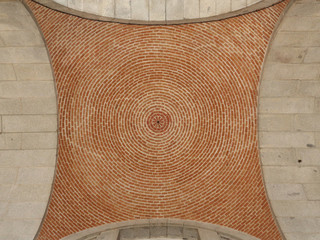 A vertical view of the architecture of an orange brick made circular dome in the Armory Place (Plaza de la Armeria) of the Royal Palace, Madrid, Spain