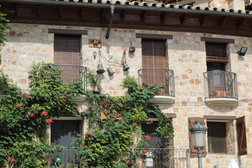 Fototapeta na wymiar Typical rural stone made house with wooden windows, wrought iron railings and climbing ivy in Alquezar, Spain