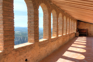 A series of brick made rounded arches on an enclosed balcony during a sunny summer in the Colegiata de Santa Maria la Mayor in Alquezar, Aragon, Spain