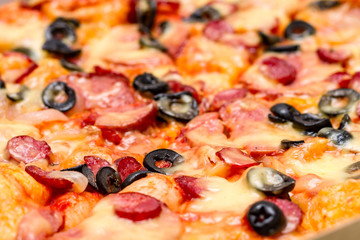 Pizza with salami, cheese and  black olives. Selective focus. Close up.