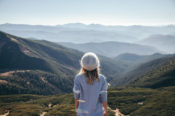 Naklejka premium rear view of female traveler looking at scenic mountains on sunny day, Carpathians, Ukraine