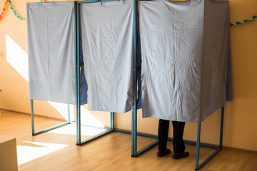 Persons voting in booths at a polling station