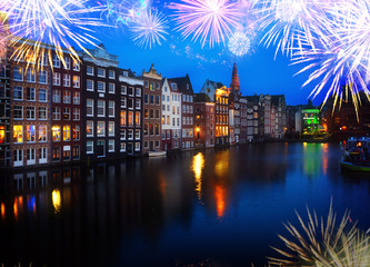 Houses over canal with mirror reflections at blue night with fireworks, Amstardam, Netherlands,